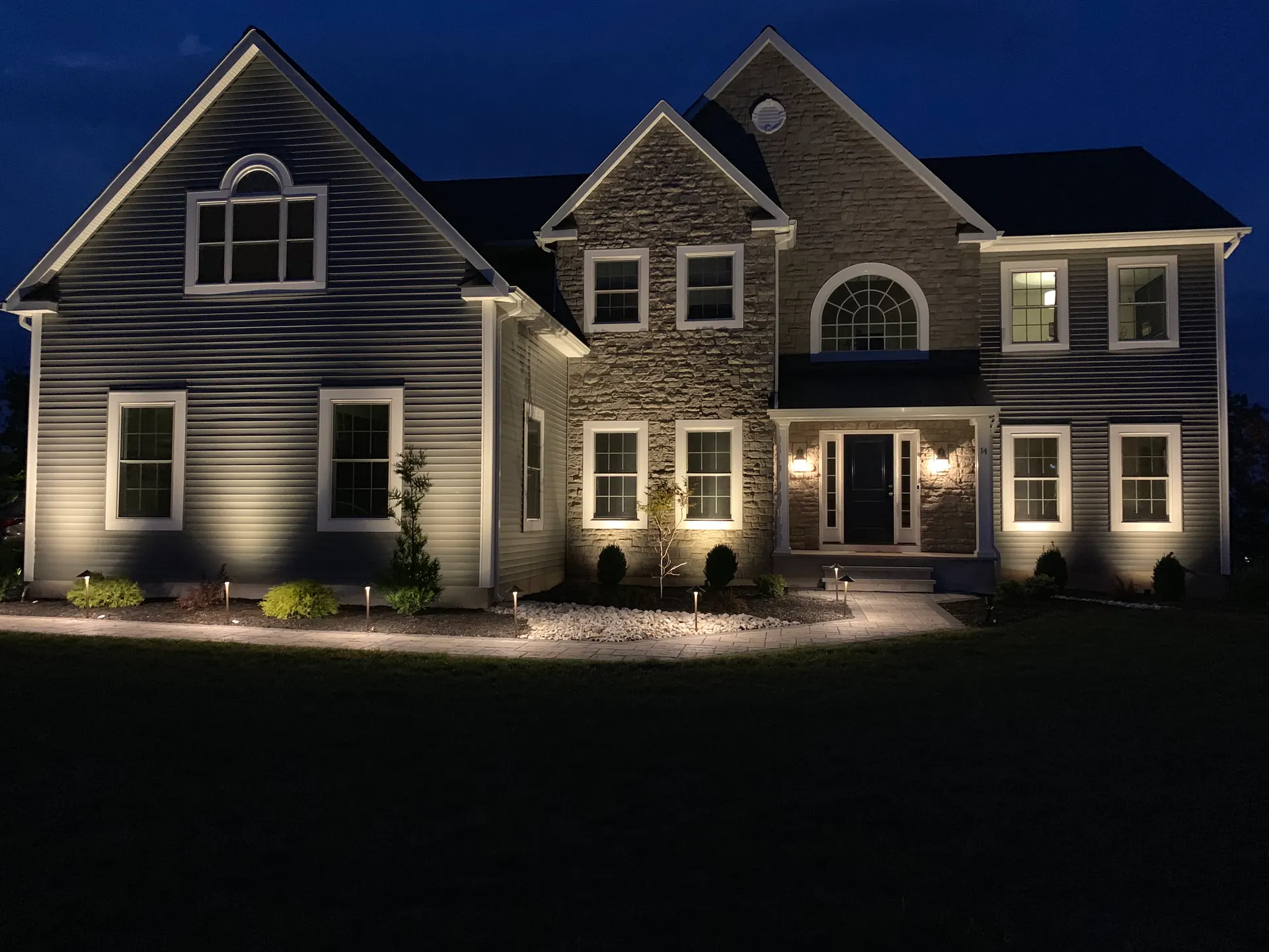 Night two-story home with even facade wash and path lights