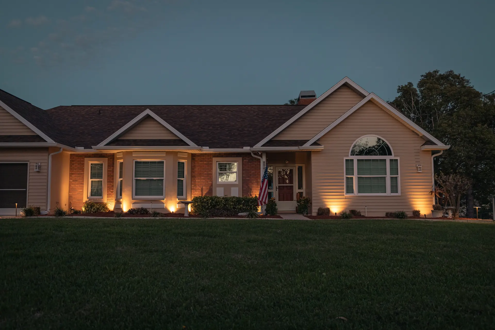 Ranch home at dusk, even warm uplighting across facade