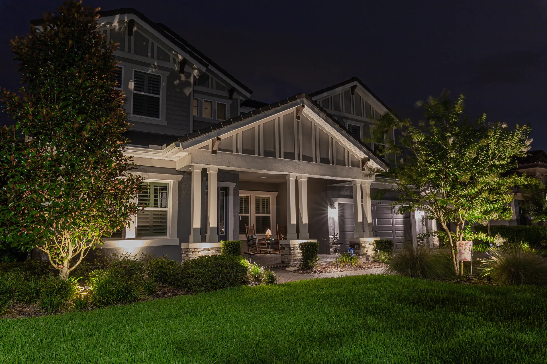Craftsman home night, uplit trees and lit porch, lush lawn, premium curb appeal