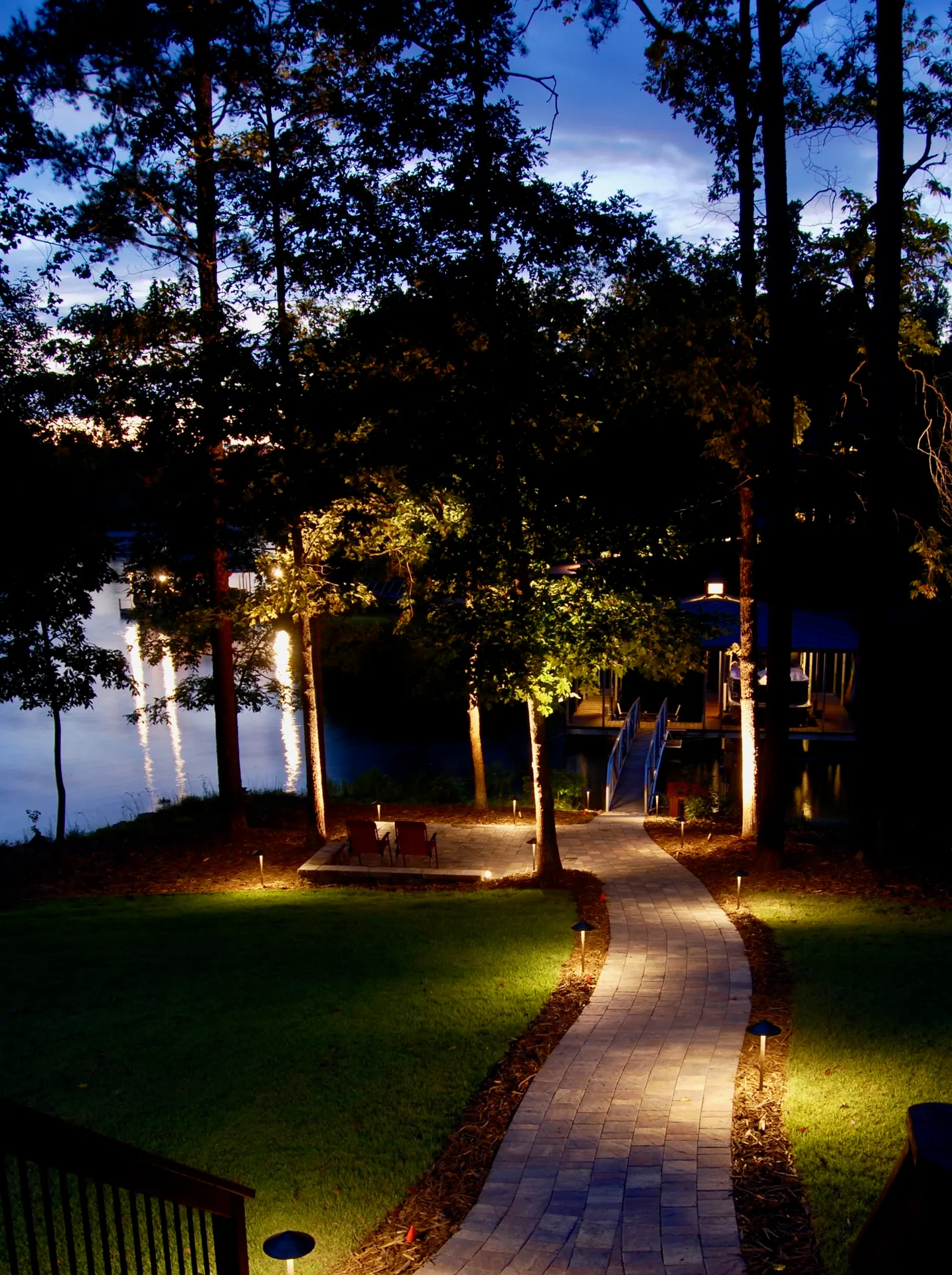 Dusk lakeside paver path with path lights and tree uplighting