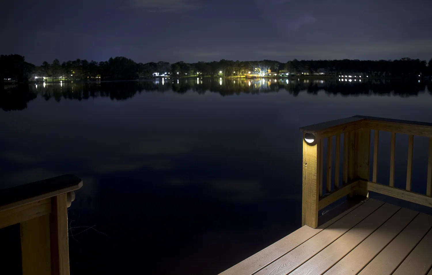 Night dock over lake, warm post light, distant shore lights reflecting