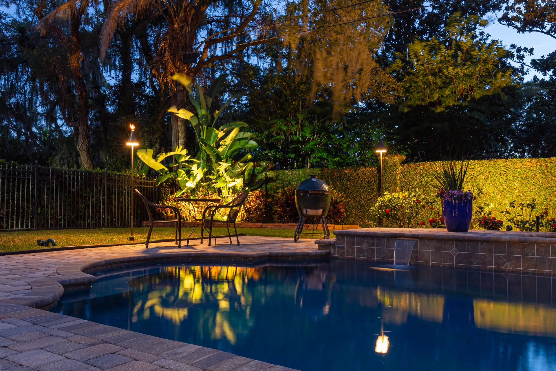 Dusk pool patio, uplit banana plant, lit bollards, blue sky reflection