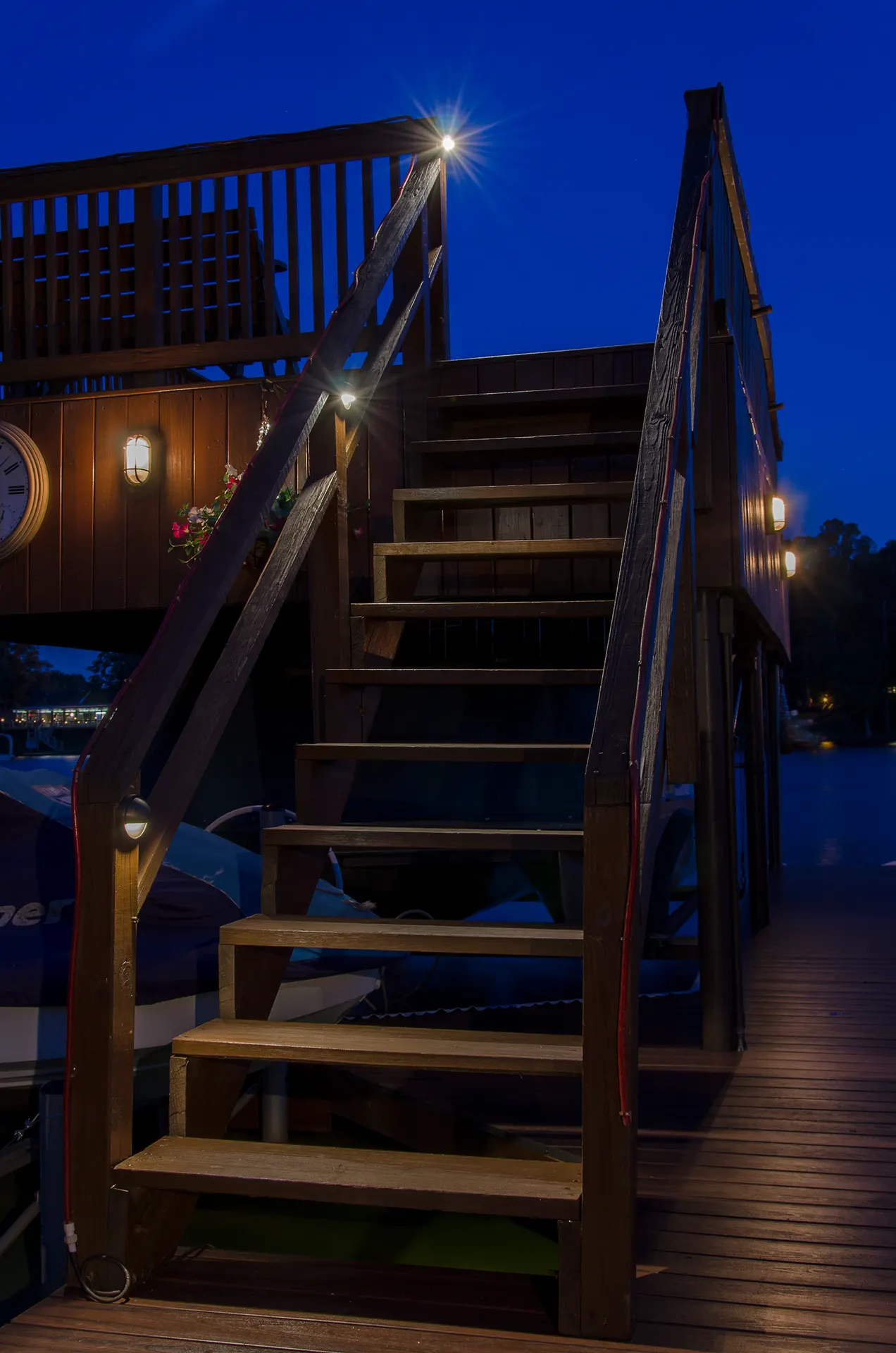 Dusk lakeside dock stairs with lit deck railing and post caps
