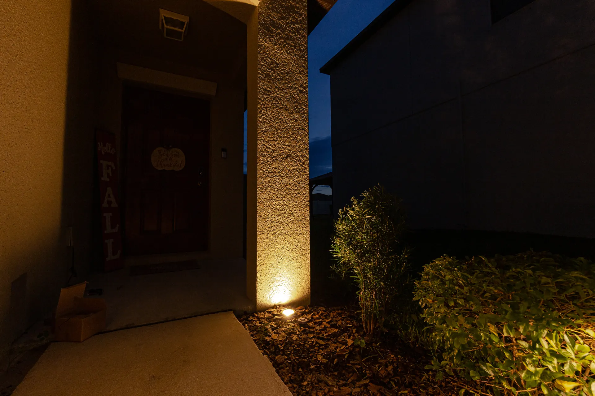 Warm white uplight on textured column, dusk sky, clean glare-free entry