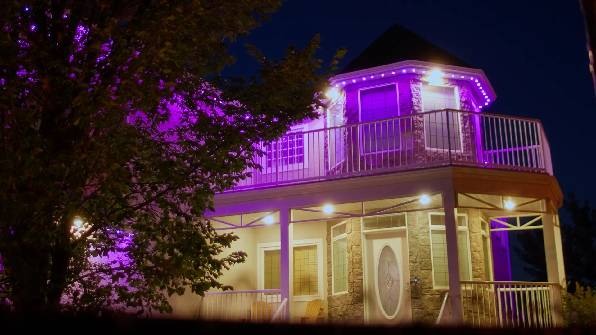 Elegant balcony turret with purple wash and warm soffits, stone facade at dusk