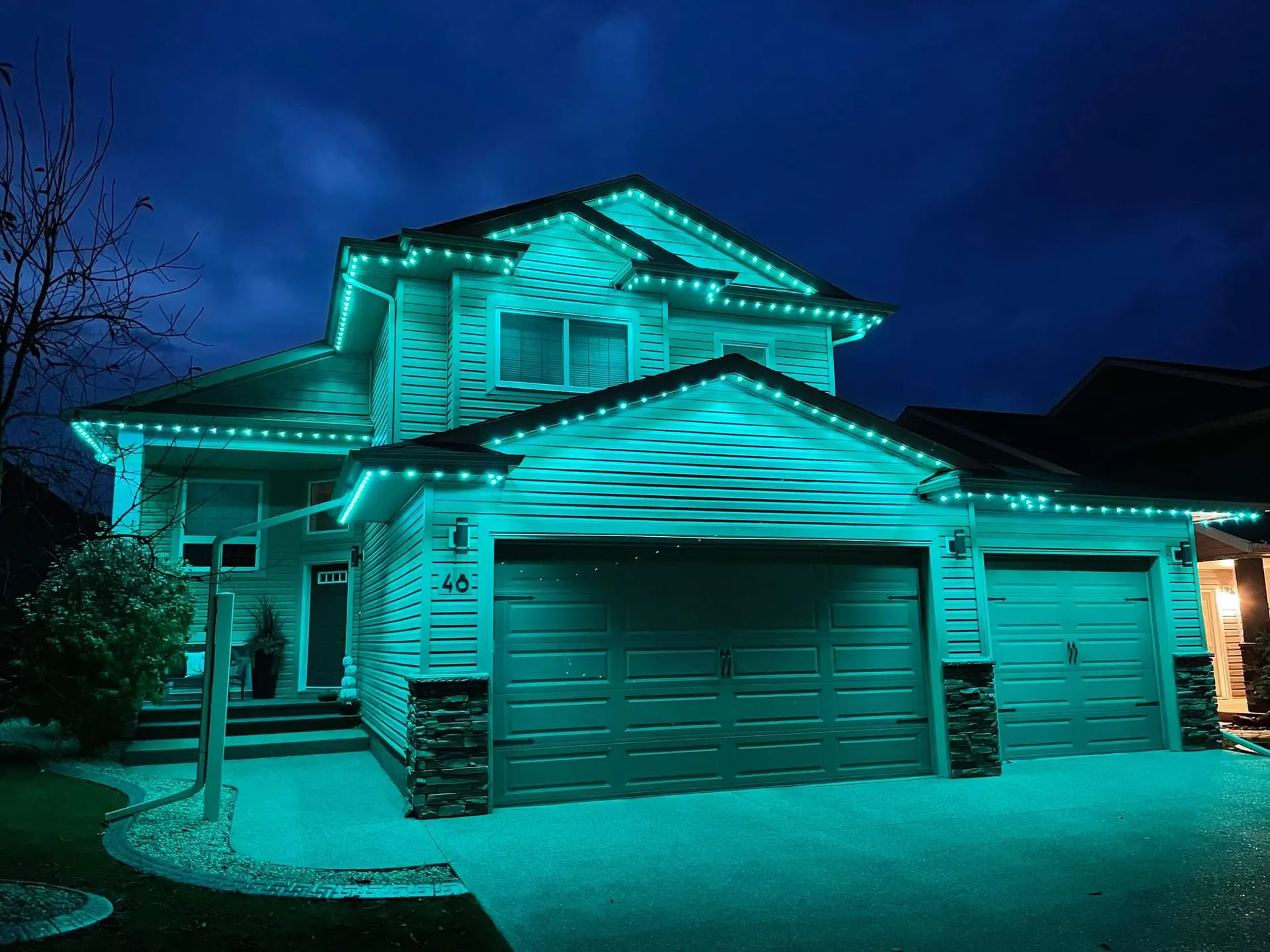 Two-story home fully outlined and washed in rich teal, crisp clean night shot