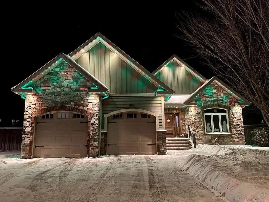 Stone craftsman home, green-white roofline color, snowy driveway