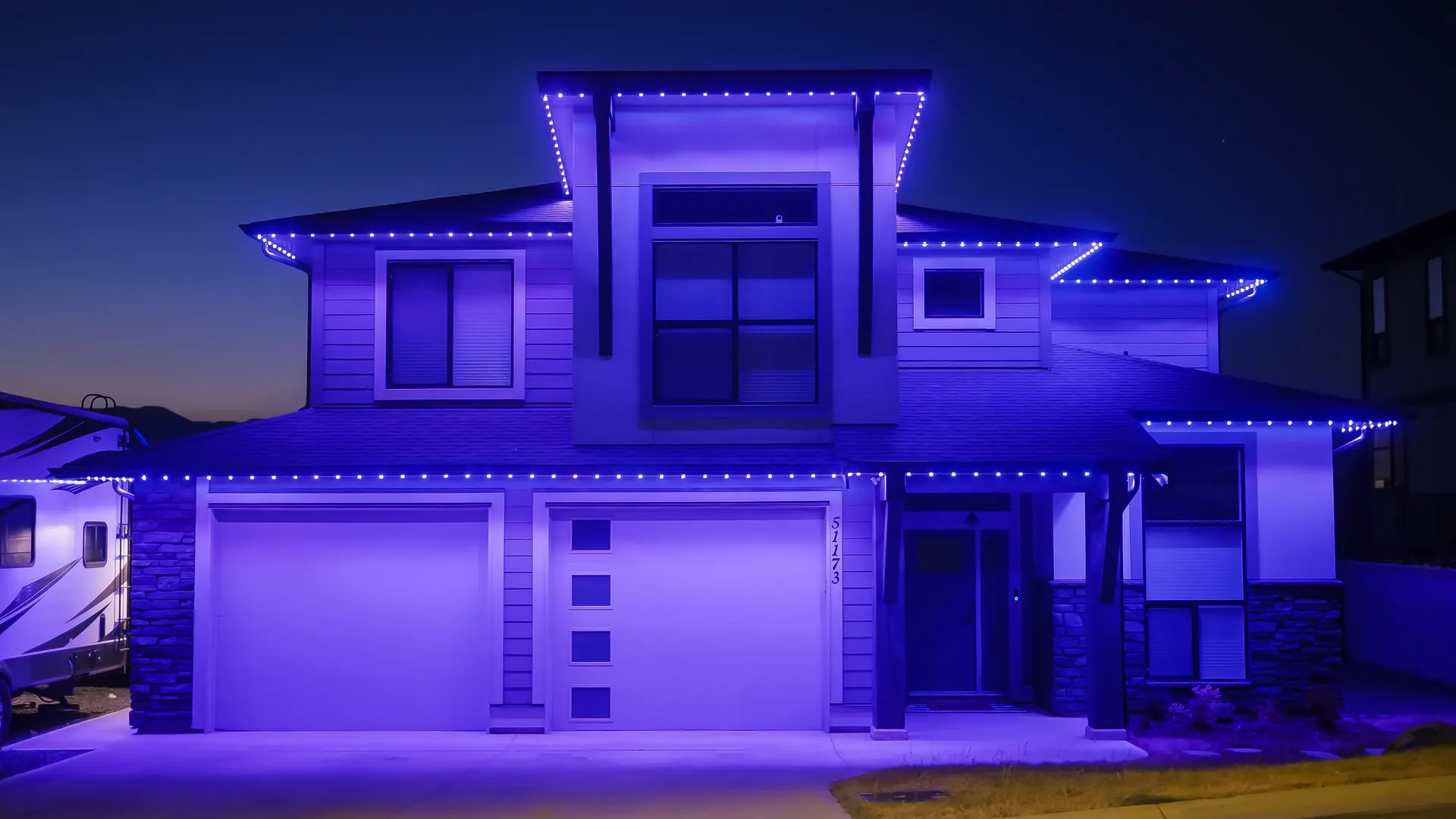 Modern home fully outlined in saturated blue permanent lighting against dusk sky