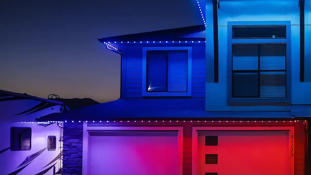 Home with permanent lighting set to blue along the upper rooflines and red over the garage at dusk