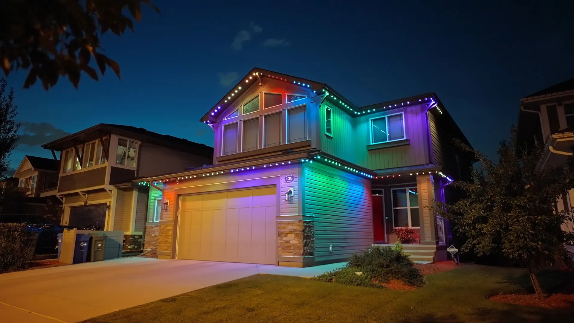 Two-story home rooflines traced in full rainbow gradient color against blue dusk