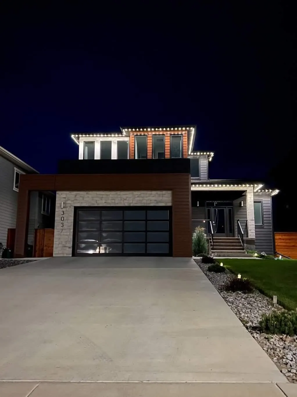 Home at dusk with warm white permanent lighting recessed along the soffit and eaves