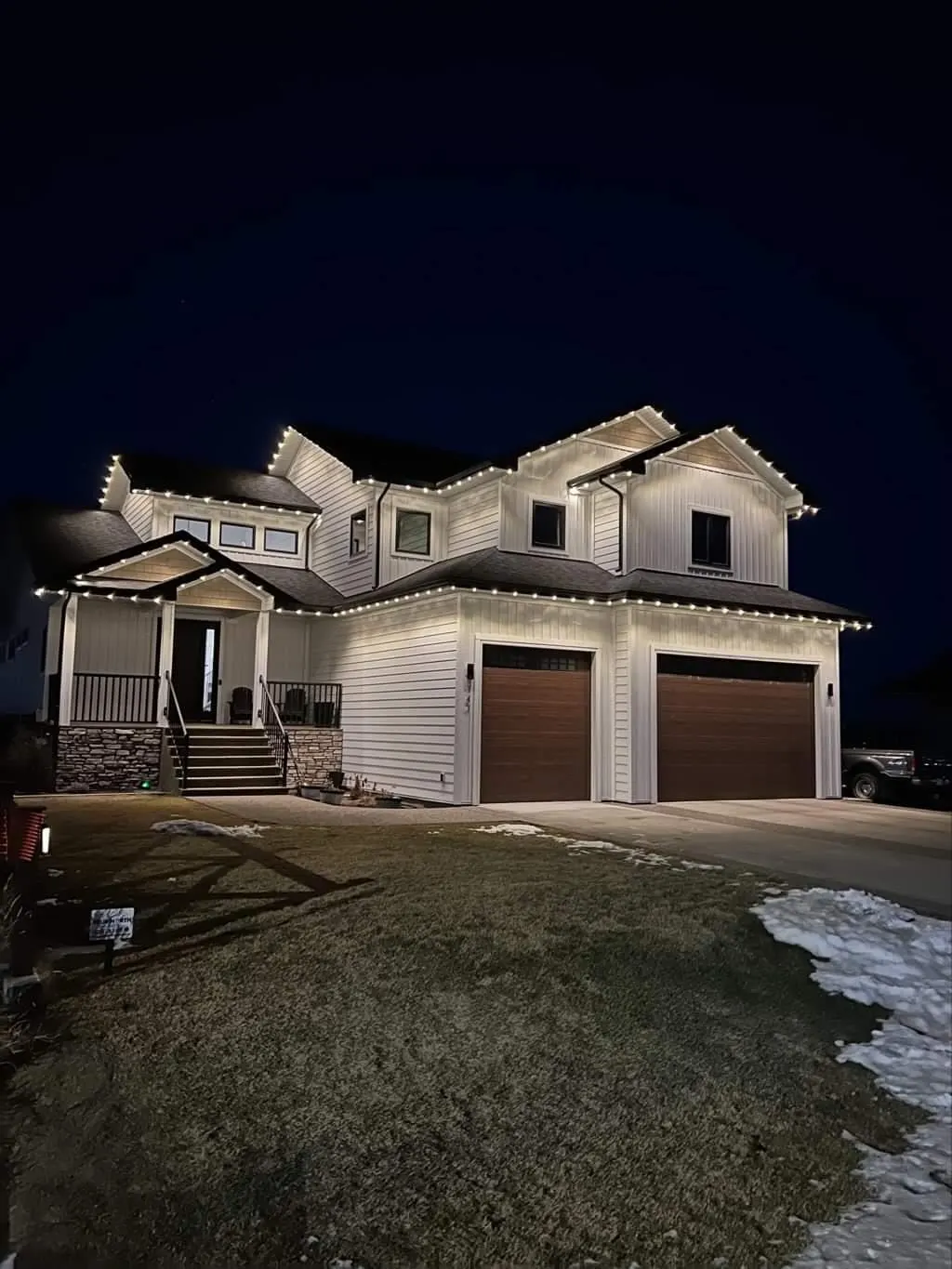 Two-story farmhouse traced in warm white, peaks eaves porch, winter night