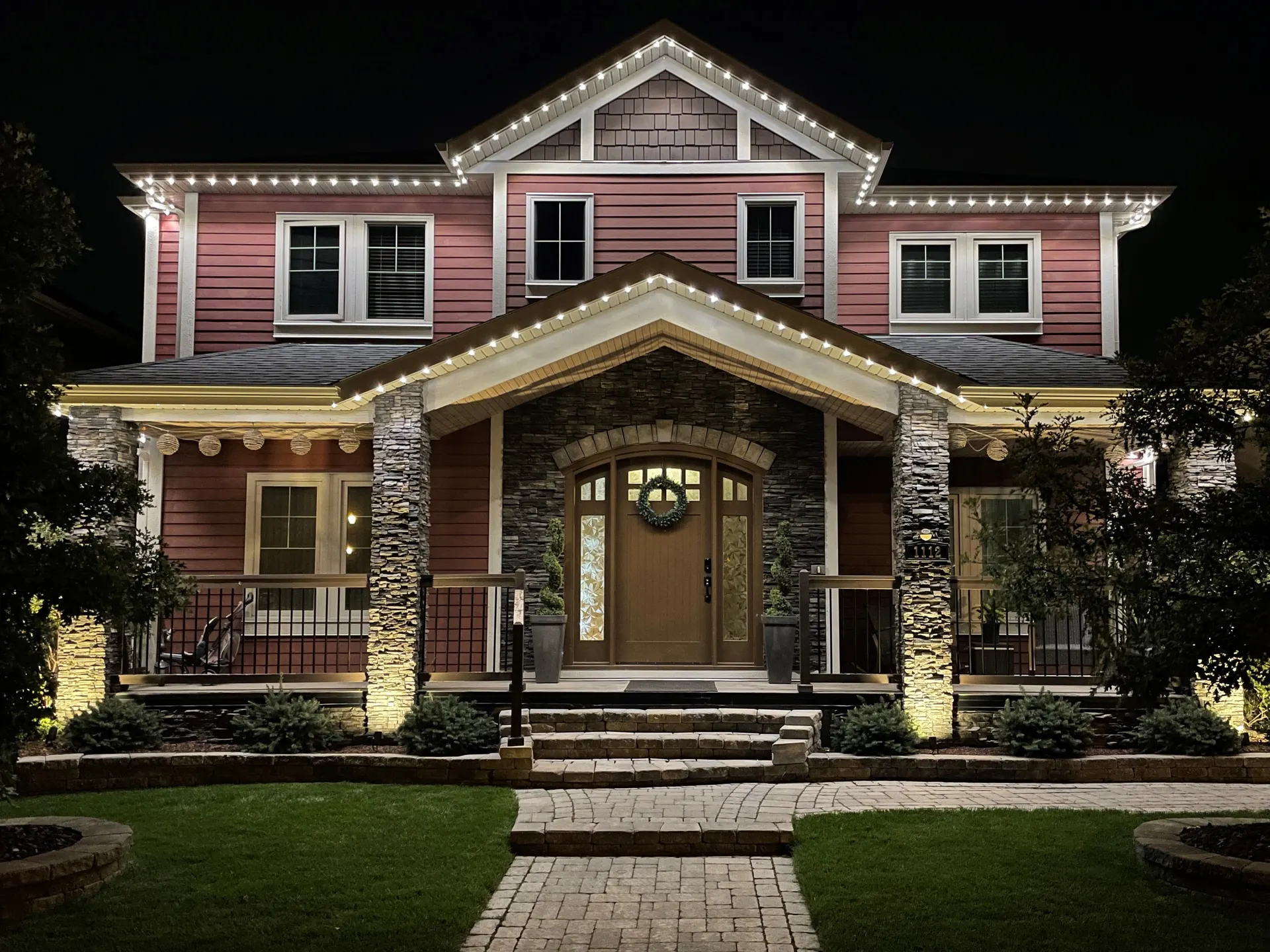 Stately home at night with warm white permanent lighting outlining the rooflines and uplit columns