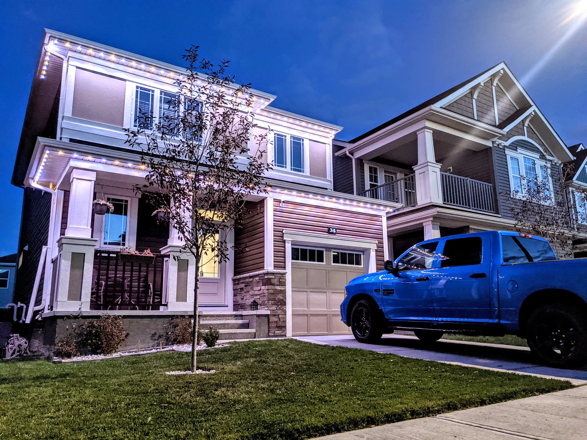 Two homes outlined in warm white at dusk, blue truck in driveway