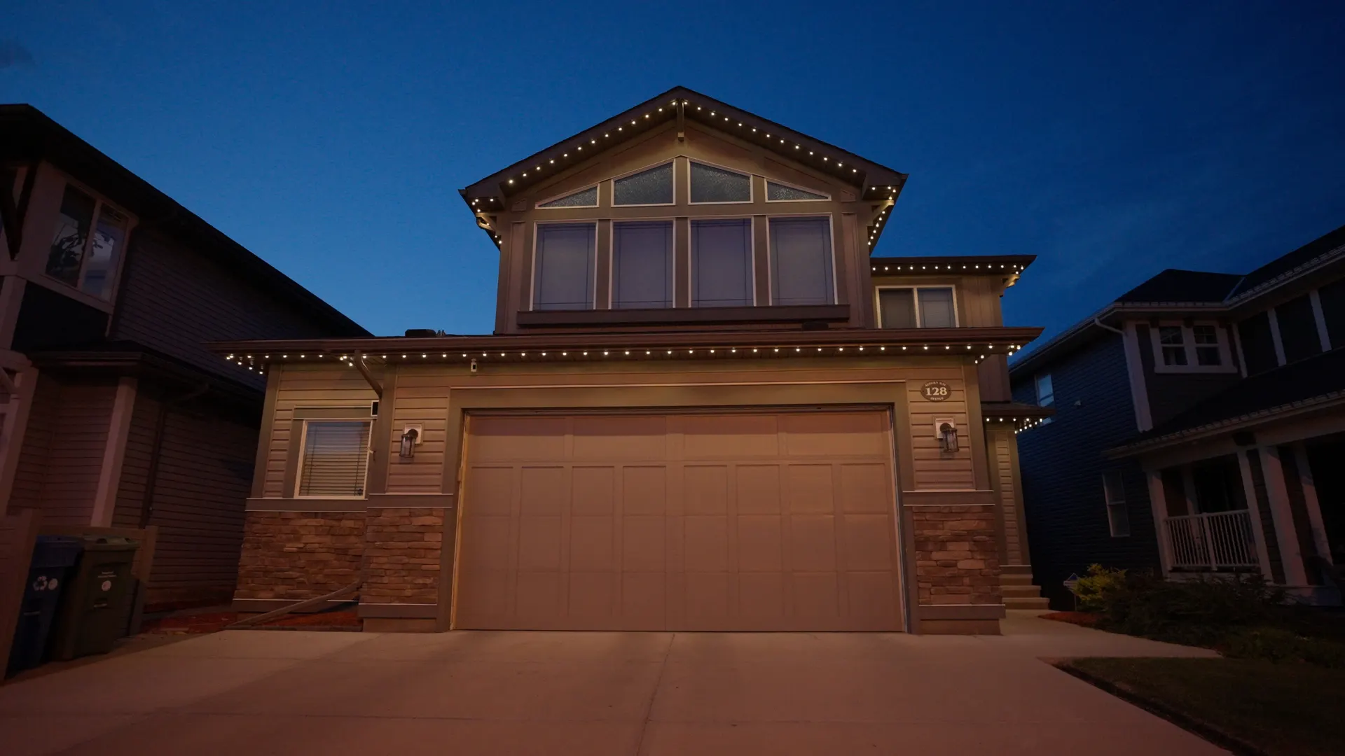 Craftsman home gable and eaves outlined in warm white at blue dusk