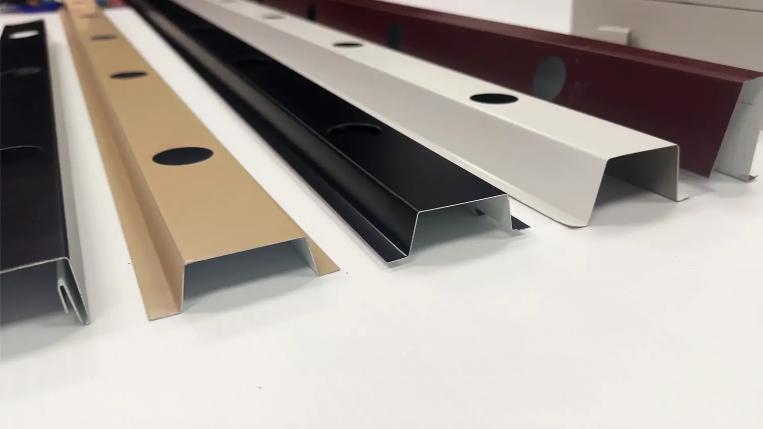 Aluminum permanent-lighting track shown in five color options including tan, black, white, and bronze, each pre-drilled for recessed LED bulbs
